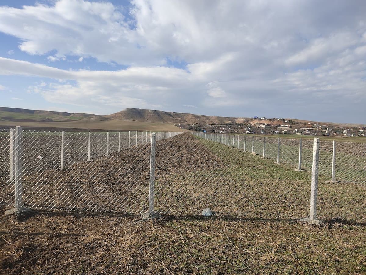 Tarla çevresine çekilmiş galvaniz örgülü tel çit ve beton direkler — Bozok Tel Örgü