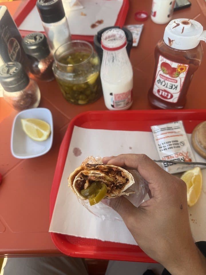 Elde tavuk döner dürüm, masada turşu ve soslar