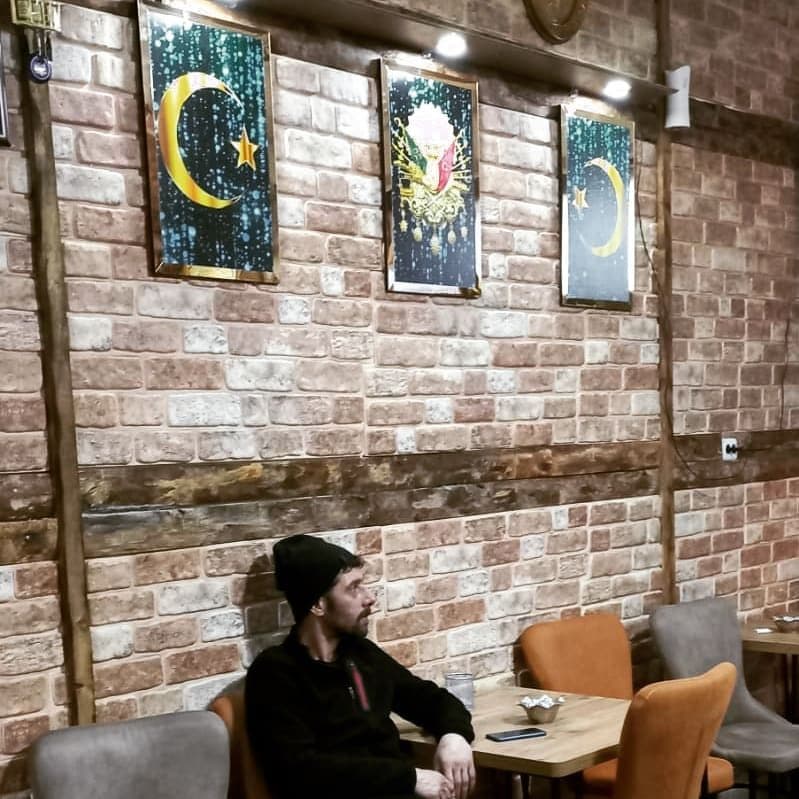 Osmanlı motifli tablolar ve tuğla duvarlı iç mekân